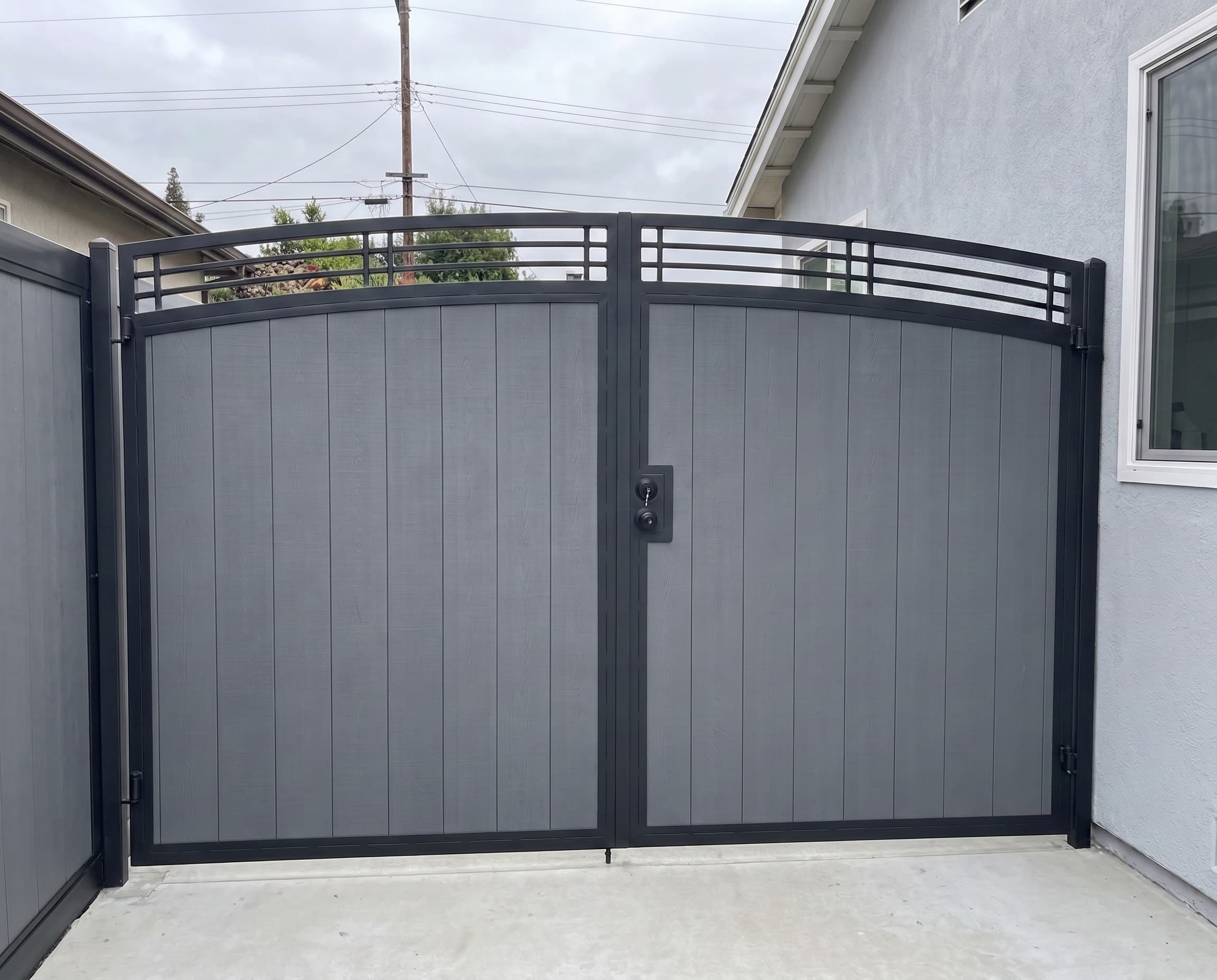 Custom Driveway Gate with vertical Slat Infill and Curved Top Rail