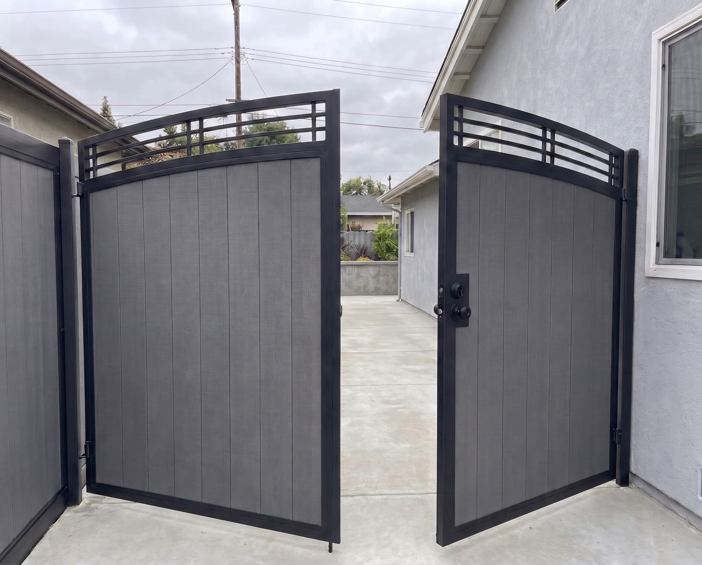 Custom Driveway Gate with vertical Slat Infill and Curved Top Rail